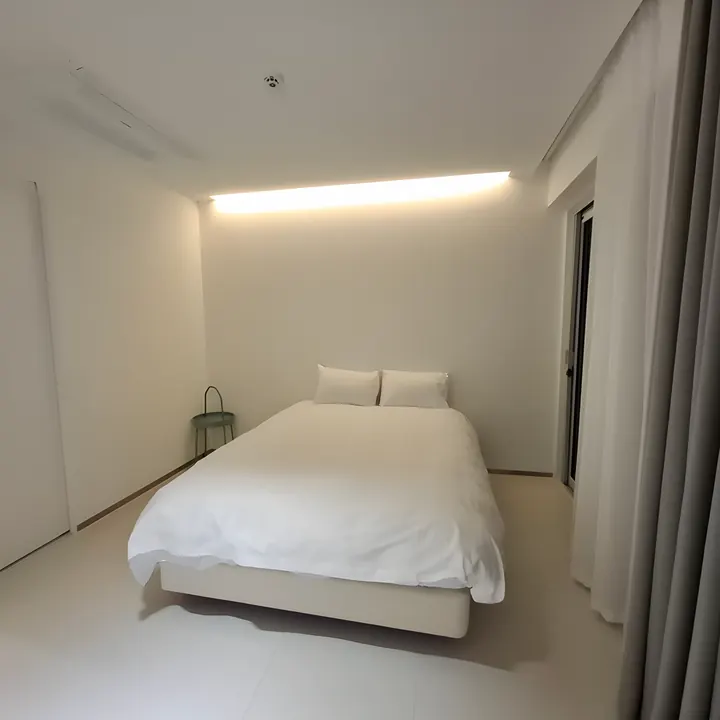간접조명 아래 침대가 놓인 침실